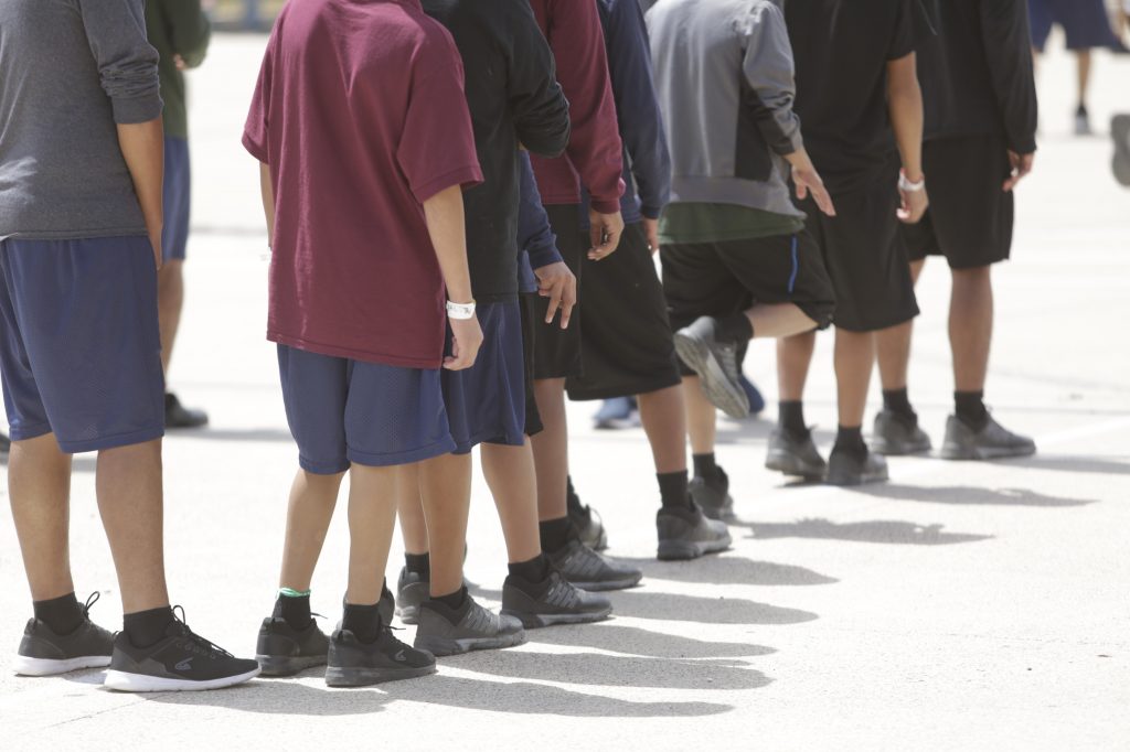 Boys 10 to 17 years old stand outside a government-contracted youth shelter in Brownsville, Texas. Ninety percent of the residents traveled to the United States alone seeking protection; the remainder were separated from their families at the border under a controversial new policy by the Trump administration.