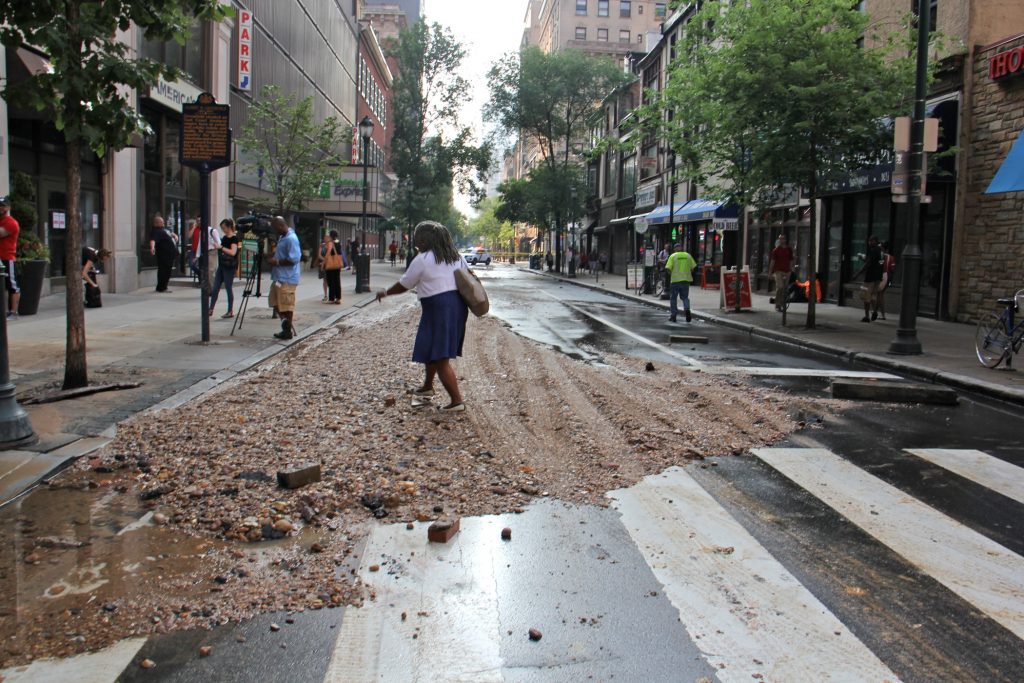 2018 07 03-e lee-center city walnut and juniper-water main break A pedestrian at Walnut and Juniper streets steps over a pile of debris left behind by a massive water main break in Center City. (Emma Lee/WHYY)