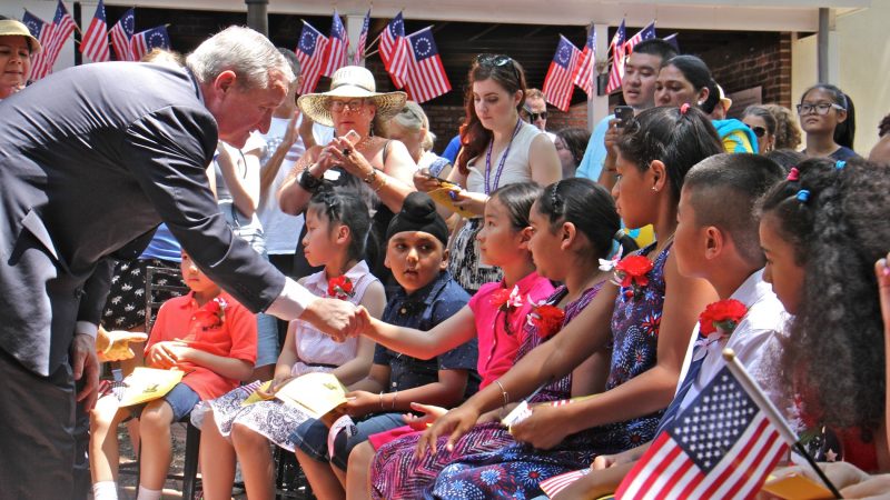 Philadelphia Mayor Jim Kenney shakes hands with each of 13 children who became U.S. citizens during a ceremony at the Betsy Ross House. (Emma Lee/WHYY)