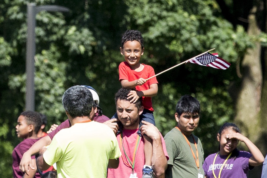 A group of immigrants detained at the Berks County Residential Center in Leesport, Pennsylvania, respond to a protest of the detention center across the street from the facility on the afternoon of July 15. At center, a young boy smiles and waves an American flag. 