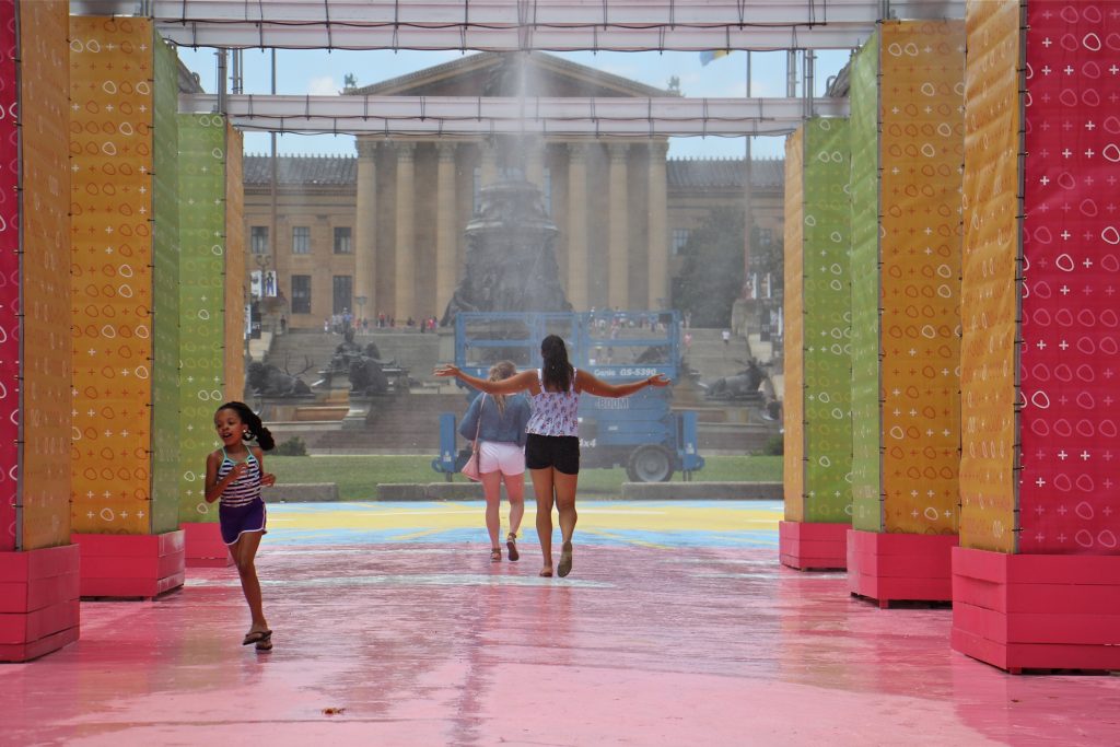 2018 07 20-e lee-philadelphia eakins oval-oval plus pop-up People cool off in the mister at the Eakins Oval pop-up park. (Emma Lee/WHYY)