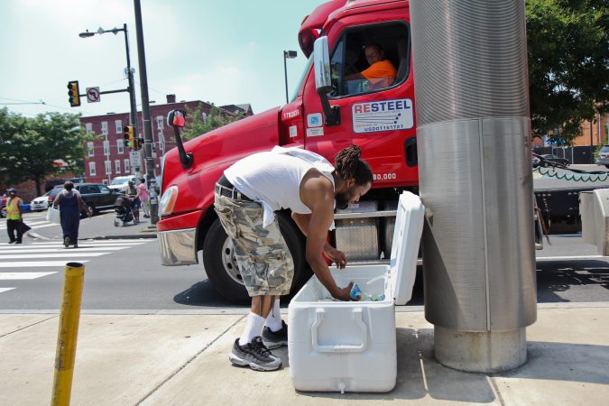 A man sells water on the median of Broad Street at Girard Avenue in the midst of a heat wave with temperatures in the mid- to upper 90s expected throughout the week. (Kimberly Paynter/WHYY)