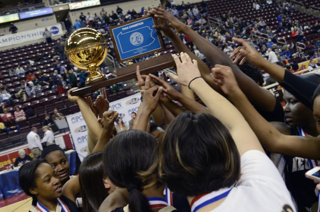 PIAA Class AA Girls Basketball Neumann-Goretti players reach for the championship trophy at the end of a PIAA high school Class AA Girls championship basketball game against Seton LaSalle in Hershey, Pa. on Friday, March 20, 2015. Nuemann-Goretti won 79 - 34.