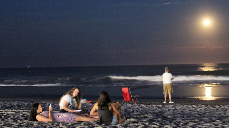 Fishermen and boardwalkers head down to the beach for the best view of a dramatic moonrise after dark. (Bill Barlow/for WHYY)