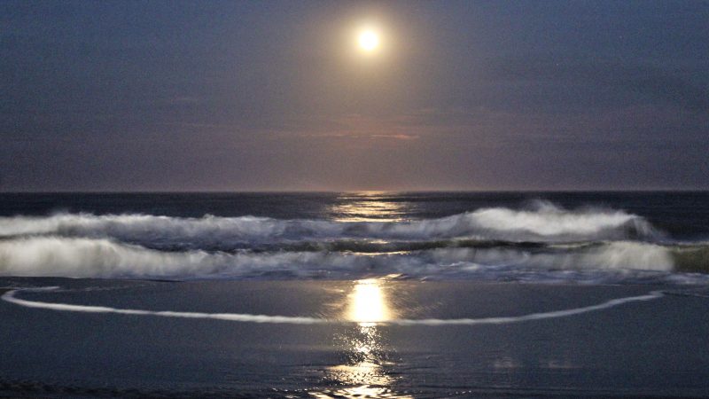Not far from the bustle and noise of the Boardwalk, the view over the ocean is calm and quiet as the waves reflect the moon. (Bill Barlow/for WHYY)

