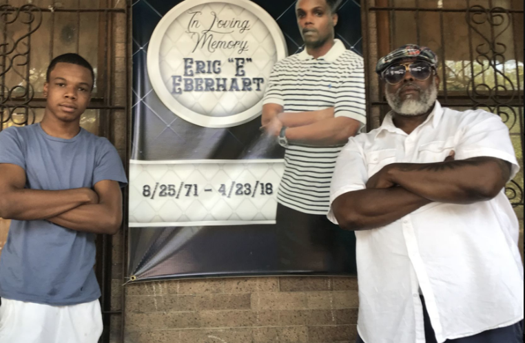 Eric Eberhart, 17, left, stands next to Shawn Wilson in front of a picture of his father, Eric Eberhart Sr., who was gunned down earlier this year. — Tribune Photo by John Mitchell