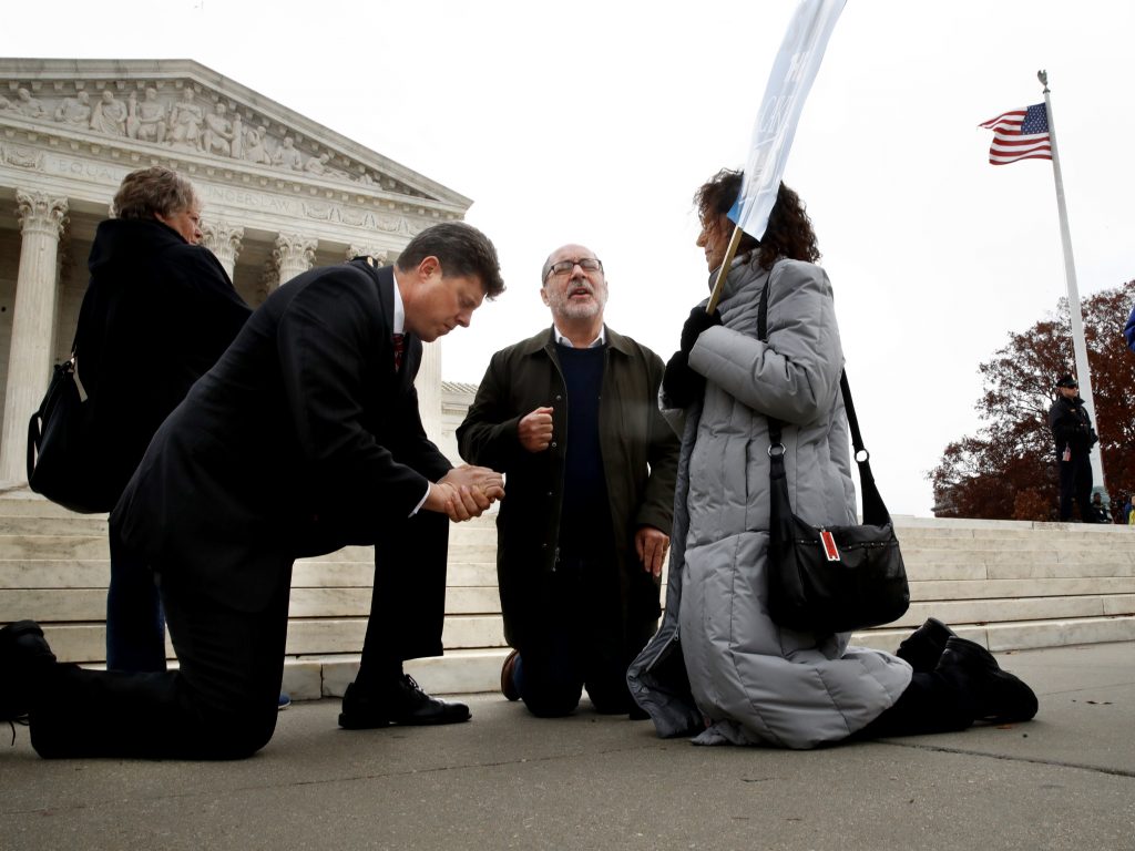 The Rev. Brad Wells, left, the Rev. Patrick Mahoney and Paula Oas, kneel in prayer in front of the Supreme Court, as the court hears the Masterpiece Cakeshop case. The Rev. Brad Wells, left, the Rev. Patrick Mahoney and Paula Oas, kneel in prayer in front of the Supreme Court, as the court hears the Masterpiece Cakeshop case. (Jacquelyn Martin/AP)