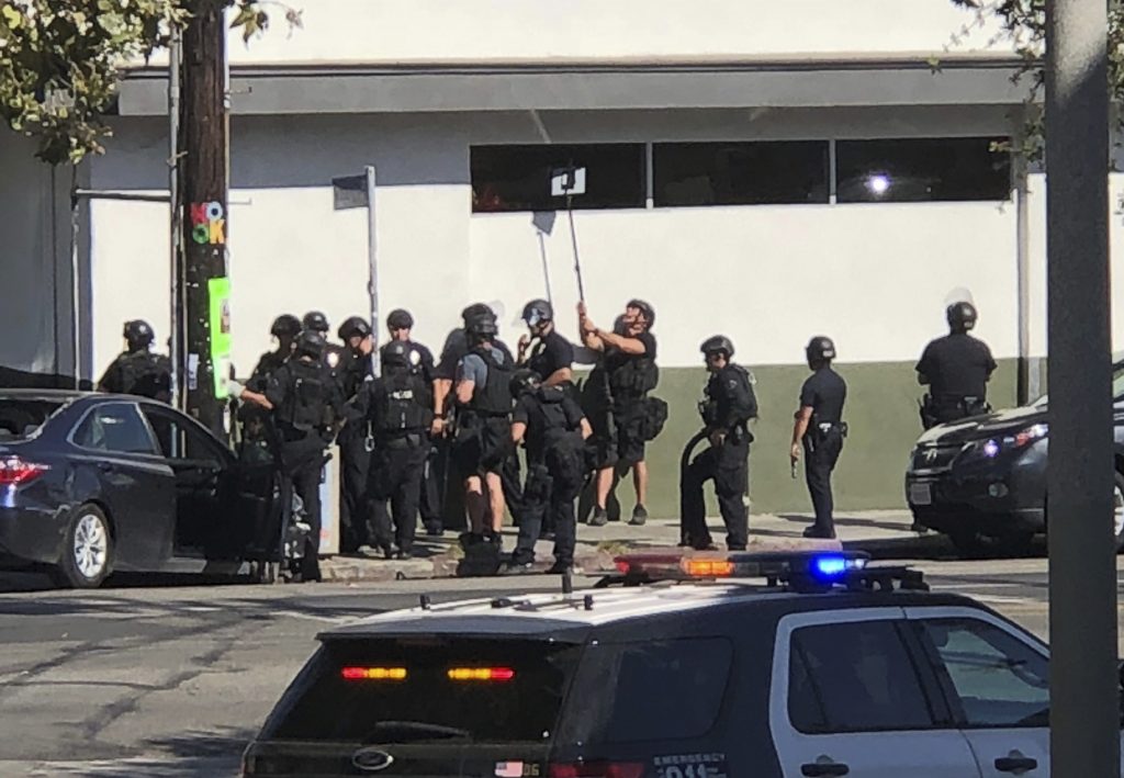 Police officers use a mirror to see inside a Trader Joe’s store in the Silver Lake neighborhood of Los Angeles on Saturday. Police believe a man involved in the standoff with officers shot a young female and his grandmother before firing at officers during a pursuit, then crashing outside the supermarket and running inside the store. Police officers use a mirror to see inside a Trader Joe's store in the Silver Lake neighborhood of Los Angeles on Saturday. Police believe a man involved in the standoff with officers shot a young female and his grandmother before firing at officers during a pursuit, then crashing outside the supermarket and running inside the store. (Christian Dunlop/AP)