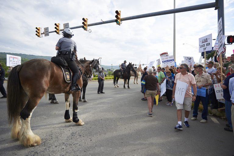 Police on horses gather a crowd of protesters towards the sidewalk on Highland Park Boulevard in Wilkes-Barre, PA. Approximately 300 protesters showed up on August 2, 2018, outside of the Make America Great Again rally. (Natalie Piserchio for WHYY)