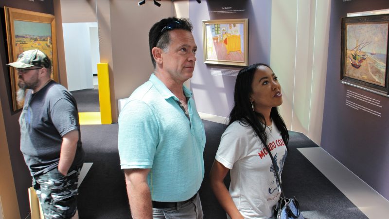 John Lippman (center) and Angelique Castro view the paintings at the pop-up van Gogh Museum at King of Prussia Mall. (Emma Lee/WHYY)