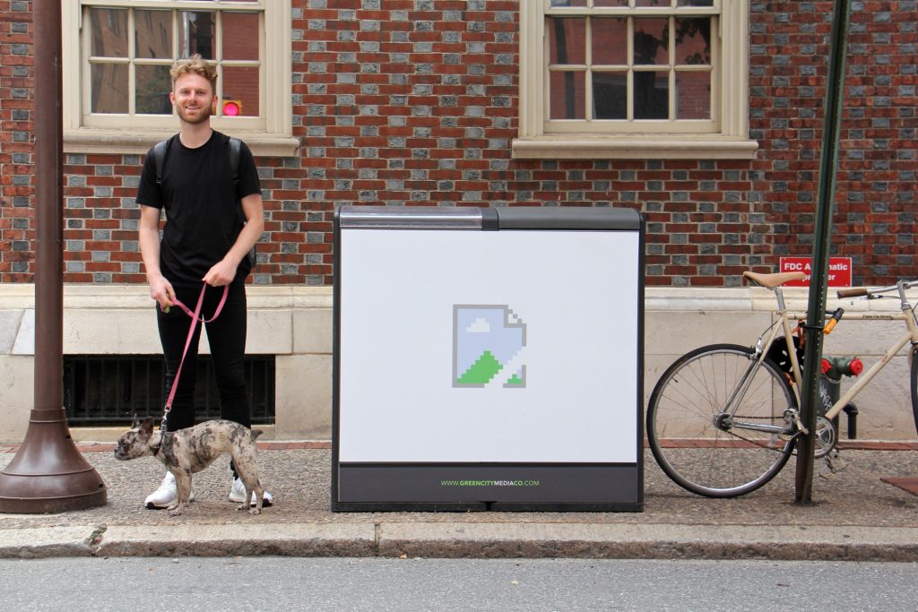 Artist Brendan Lowry stands beside his contribution to the Trashcan Takeover project at 17th and Locust streets.