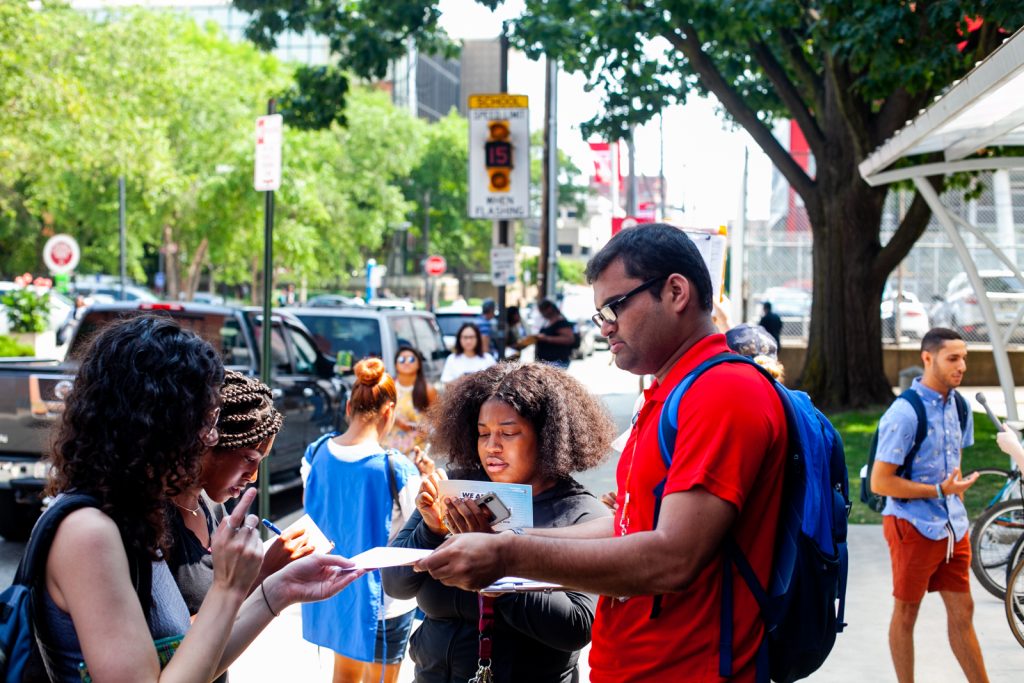 Razin Karu, a Temple University senior and fellow with NextGen, passes out surveys to fellow students that could be redeemed for free ice cream. (Brad Larrison for WHYY)