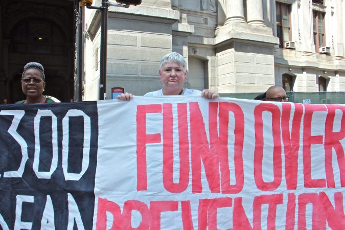 Sandra Collett, 58, (center) who lost her partner to an overdose and has been in recovery for nine years, joins about 30 other activists at City Hall calling for overdose prevention sites in Philadelphia. (Emma Lee/WHYY)