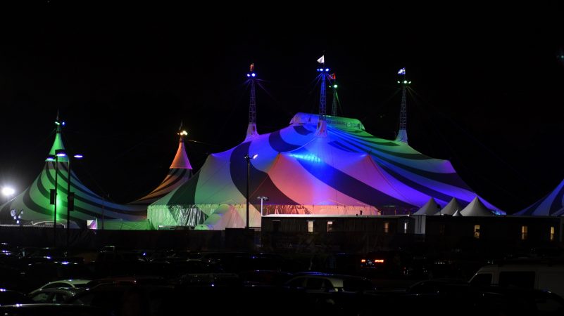 Cirque’s Grand Chapiteau is seen lit up in vibrant colors reflecting off the white surface, as it is located next to the Greater Philadelphia Expo Center, in Oaks, Pa. To achieve a higher level of sustainability the Toronto-based Cirque changed its iconic big tops from blue and yellow to white and grey. (Bastiaan Slabbers for WHYY)