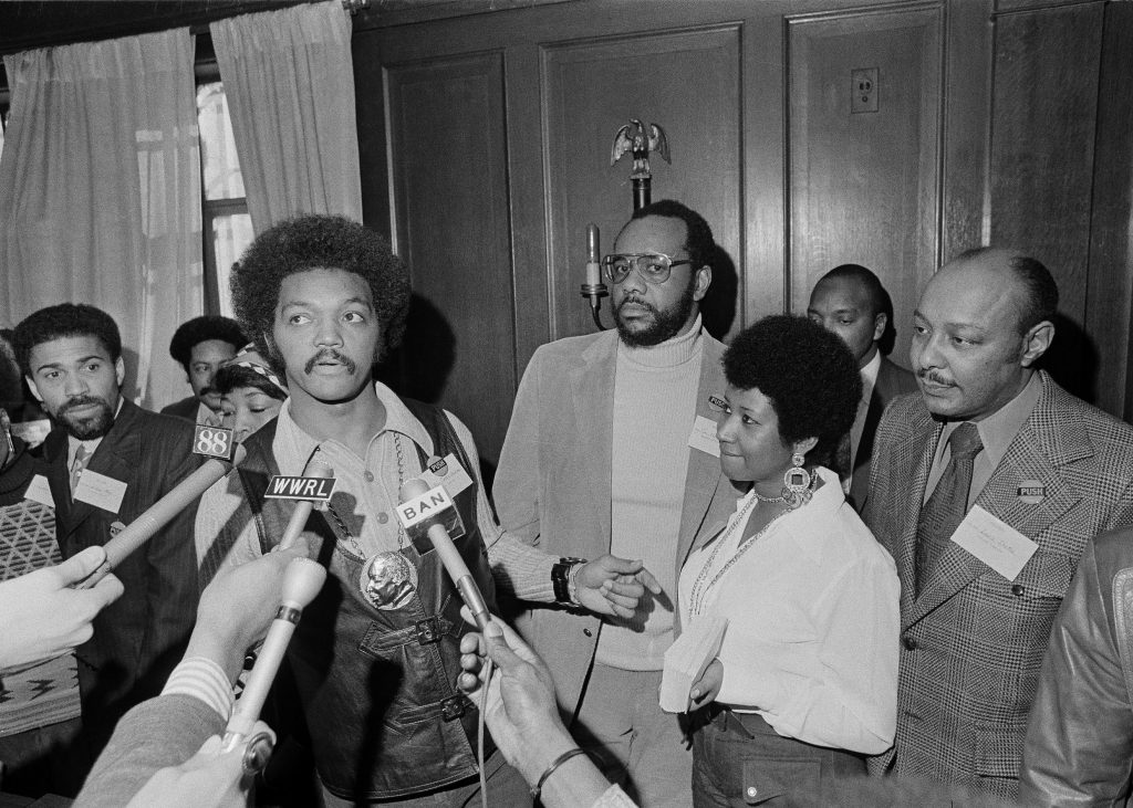 Rev. Jesse Jackson speaks to reporters at the Operation PUSH Soul Picnic at the 142nd Street Armory in New York, March 26, 1972. Left to right are: Betty Shabazz, behind Jackson, widow of Malcolm X; Jackson; Tom Todd, vice president of PUSH; Aretha Franklin and Louis Stokes. PUSH stands for People United to Save Humanity. (AP Photo/Jim Wells)
