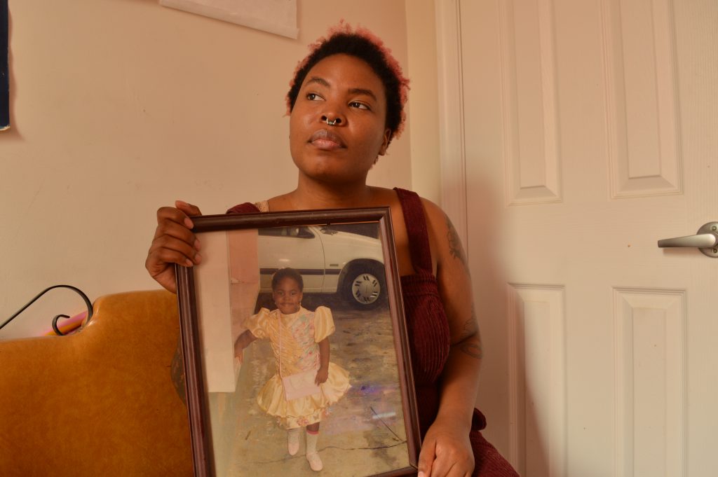 Adesola Ogunleye_by Liz Tung Adesola Ogunleye holds a picture of herself as a young child. She says childhood abuse has played into the anxiety she deals with now, as an adult. (Liz Tung/WHYY)