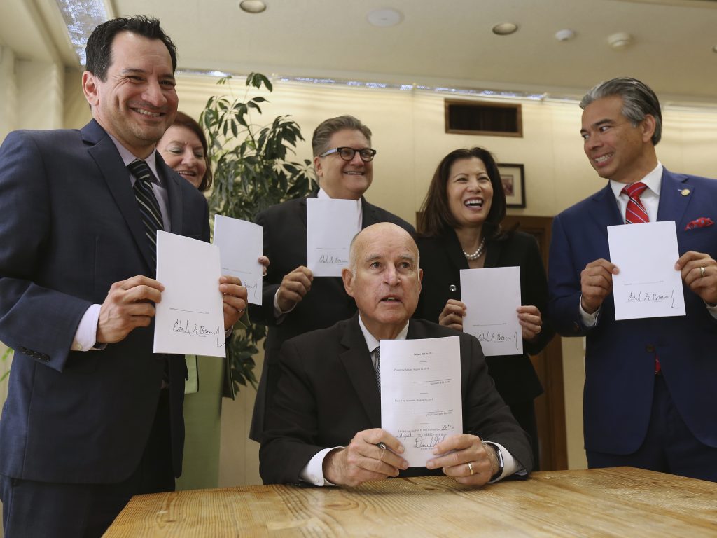 Gov. Jerry Brown holds a copy of a bill to end bail he signed Tuesday, Aug. 28, in Sacramento, Calif. The bill, co-authored by state Sen. Bob Hertzberg, D-Van Nuys, third from right, and Assemblyman Rob Bonta, D-Alameda, right, makes California the first state to eliminate bail for suspects awaiting trial. It goes into effect in October 2019. Gov. Jerry Brown holds a copy of a bill to end bail he signed Tuesday, Aug. 28, in Sacramento, Calif. The bill, co-authored by state Sen. Bob Hertzberg, D-Van Nuys, third from right, and Assemblyman Rob Bonta, D-Alameda, right, makes California the first state to eliminate bail for suspects awaiting trial. It goes into effect in October 2019. (Rich Pedroncelli/AP)