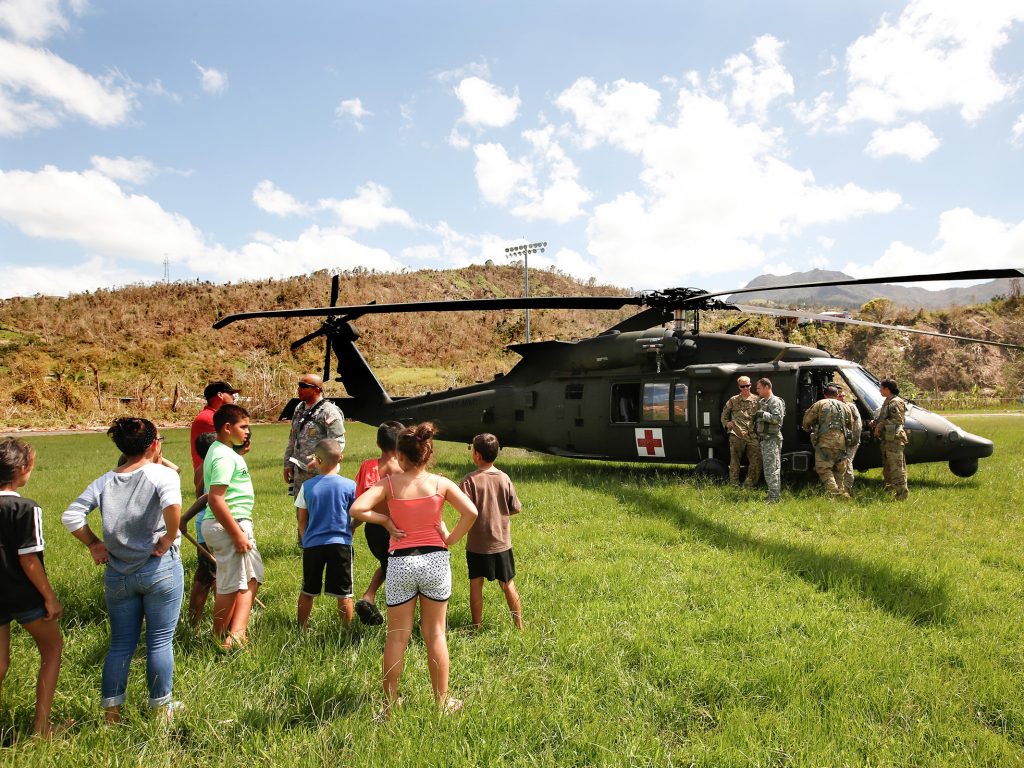 In the mountain town of Juyaya, Puerto Rico, last October, children watched as U.S. Army helicopters brought a team of physicians to assess the medical needs of the local hospital and residents. Going forward, health economists say, the U.S. territory will need continued federal help to deal with its overwhelming Medicaid expenses. In the mountain town of Juyaya, Puerto Rico, last October, children watched as U.S. Army helicopters brought a team of physicians to assess the medical needs of the local hospital and residents. Going forward, health economists say, the U.S. territory will need continued federal help to deal with its overwhelming Medicaid expenses.
(Carolyn Cole/Los Angeles Times via Getty Images)