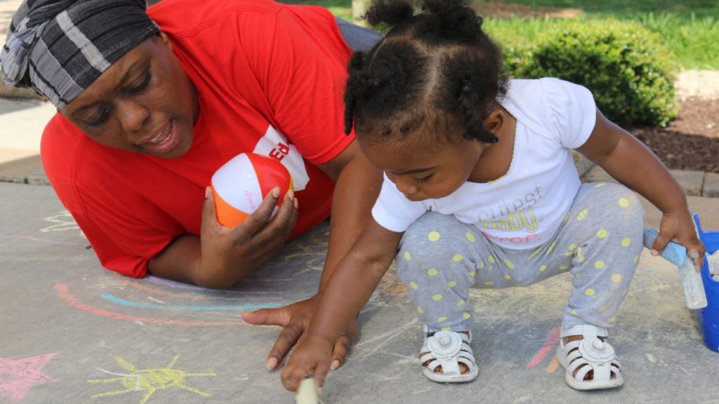 hechinger16x9 Marletha Muhammad helps her daughter, Khanila, spell her name with chalk at a June playgroup meeting in Rocky Mount, North Carolina The purpose of the meetings is to encourage healthy interactions between parents and their young children. (Liz Bell/The Hechinger Report)