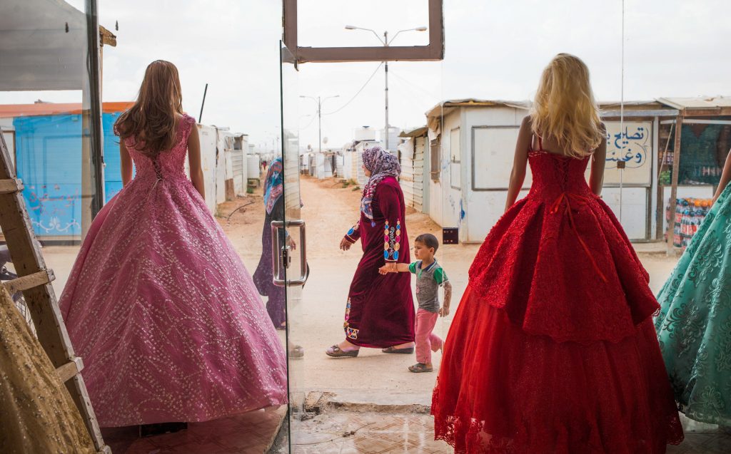 Wedding dresses come in bold hues at Salon Al Fardous — Paradise Salon. The rent-a-gown shop looks out on the temporary housing and makeshift stores in the Zaatari refugee camp in Jordan. (Adib Chowdhury)