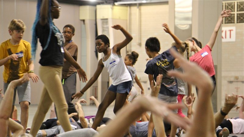 Members of the children's troupe wade through a sea of waving arms during a rehearsal for 