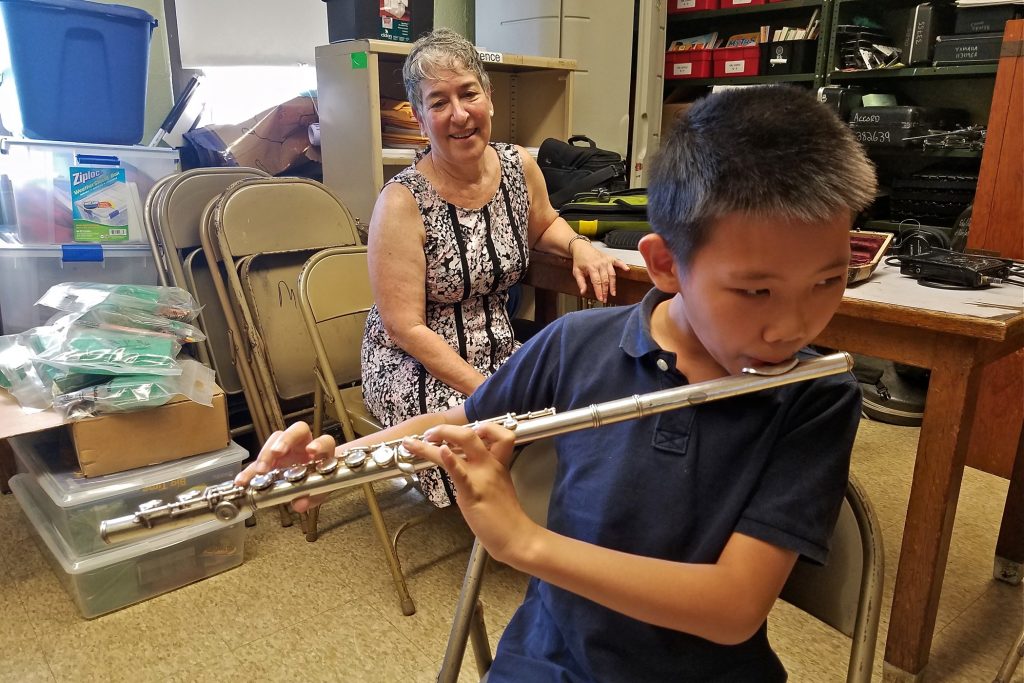2018 09 06-p crimmins-leo zhang tobie hoffman-philadelphia mayfair school-symphony for broken orchestra Leo Zhang, a student at Mayfair Elementary, will learn to play on a flute repaired through the Broken Orchestra program. Behind him is Tobie Hoffman, who played the flute in the