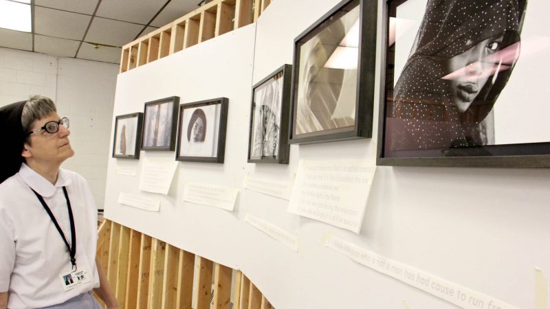 Sister Elaine George takes in a series of self portraits by Afaq, an artist who identifies herself by her first name only. (Emma Lee/WHYY)