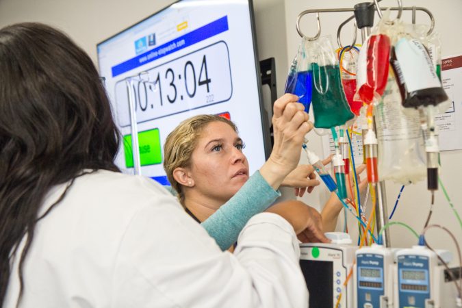 Bianca Marinez, a registered nurse at Penn, examines the IV of a dummy patient at a 