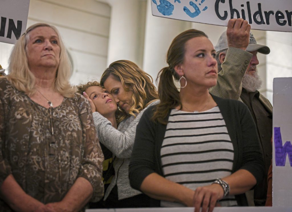 Clergy Abuse Civil Lawsuits Carolyn Fortney, center, hugs her son Elias, 11, during a press conference in the state Capitol Building on Monday, Sept. 24, 2018, in support of legislation that would change the statute of limitations for child sex crimes. Carolyn is one of five sisters in the Fortney family to suffer from abuse by a priest. Others in the photograph are Judy Deaven, left, whose son Joey Behe was abused by a priest and died of an overdose in 2015; Carolyn's sister Patty Fortney-Julius, i stripped shirt, who was also abused, and the sisters' father, Edward Fortney, right. (Steve Mellon/Pittsburgh Post-Gazette via AP)