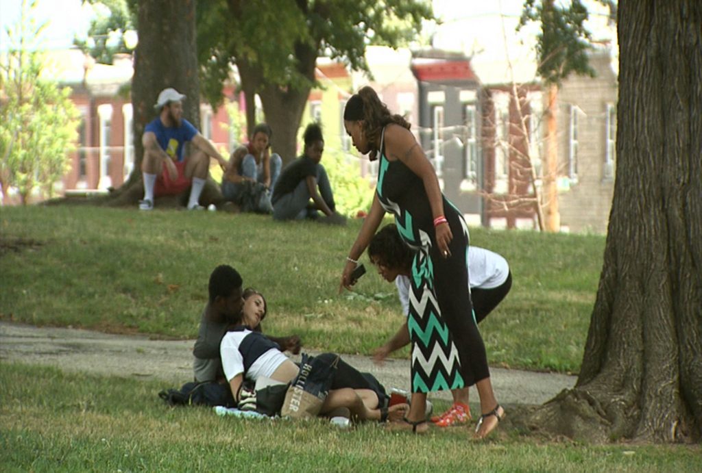 Jasmine helping sized Jasmine Johnson (right), offers Narcan to people using drugs in McPherson Square Park in Kensington. The man refused her offer because he maintained the woman was breathing, and did not want to risk sending her into withdrawal. (Erika Schroeder/WHYY)