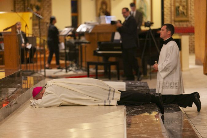 Bishop Dennis Sullivan lying prostrate before the altar, before giving the homily during an evening of prayer for the victims of abuse on September 28, 2018 in Blackwood, New Jersey. (Miguel Martinez  for WHYY)