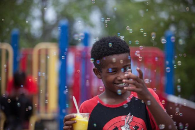 Anthony Payton, 10, of Chester County, plays with bubbles on a playground at Strawberry Mansion Day. (Emily Cohen for WHYY)