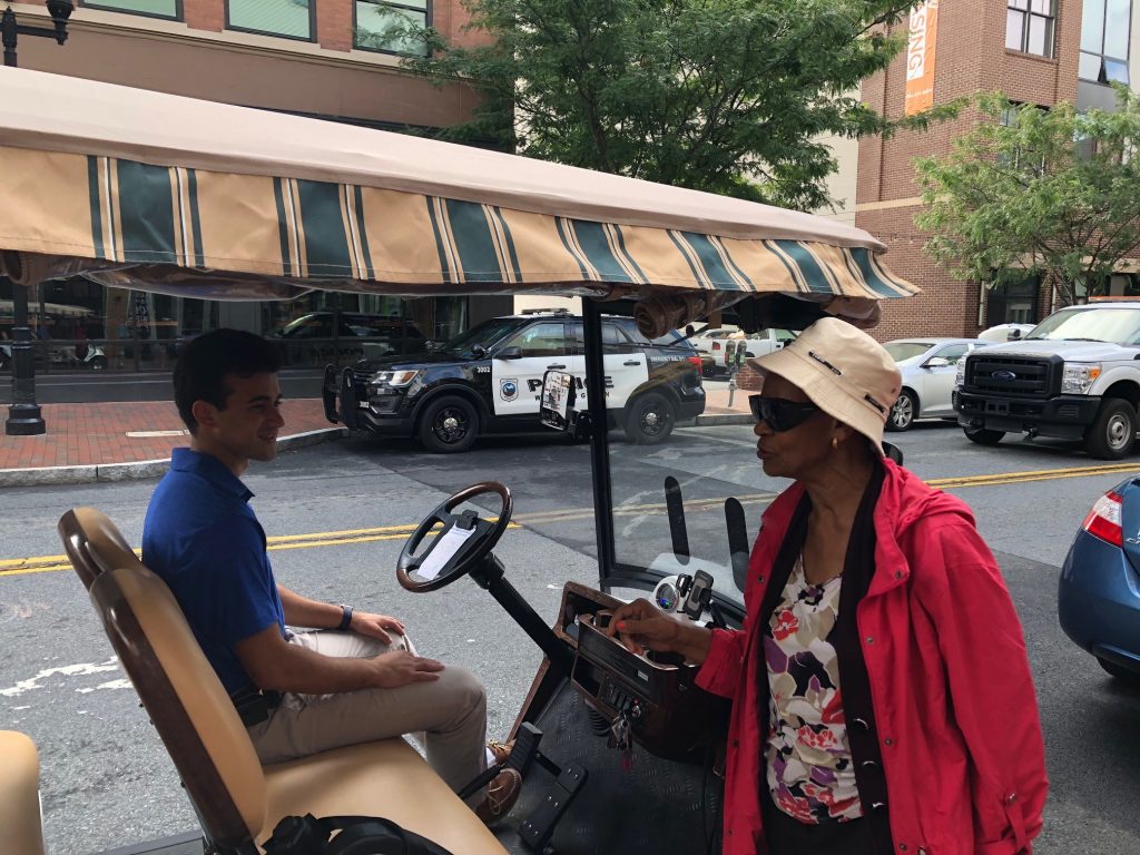 golf cart Wilmington taxi Eunice LaFate quizzes Andrew Cercena about the new golf cart taxi service he's starting for Buccini/Pollin Group. (Cris Barrish/WHYY)
