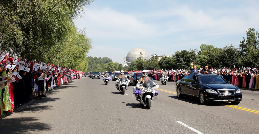 South Korean President Moon Jae-in and North Korean leader Kim Jong Un stand and wave in an open-air Mercedes-Benz as thousands of people welcome their motorcade in Pyongyang.