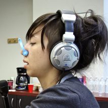 Pulse reporter Liz Tung, her nose clamped shut to prevent her sense of smell from interfering with her experience of taste, accepts a sample from behavioral geneticist Danielle Reed. (Emma Lee/WHYY)