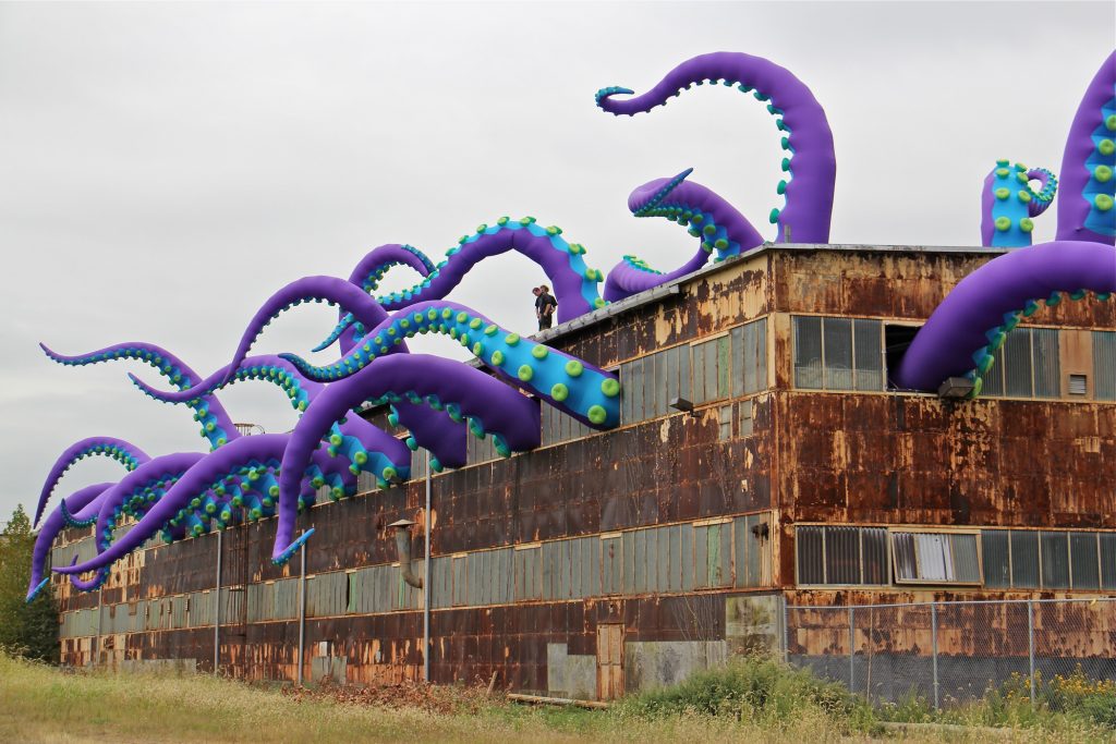 2018 10 05-e lee-philadelphia navy yard-tentacles art installation lead Giant purple green and blue tentacles protrude from the windows of a dilapidated warehouse at the navy yard