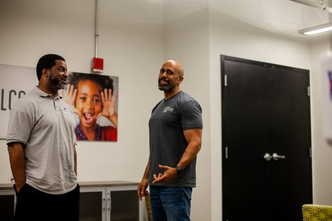 Sharif El-Mekki (left), principal at Mastery Charter's Shoemaker campus and Miles WIlson, CEO and President of Education Works chat in the office of Wilson's organization. (Brad Larrison for WHYY)