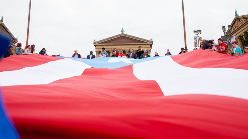 A large Puerto Rican flag is laid on the steps of the Philadelphia Museum of Art. A group of activists marched the Benjamin Franklin Parkway to commemorate the people who died in Hurricane Maria in Puerto Rico. (Miguel Martinez for WHYY)