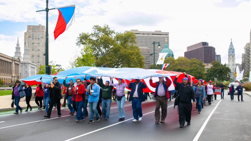 A group of activists march on  the Benjamin Franklin Parkway to commemorate the people who died in Hurricane Maria in Puerto Rico. (Miguel Martinez for WHYY)