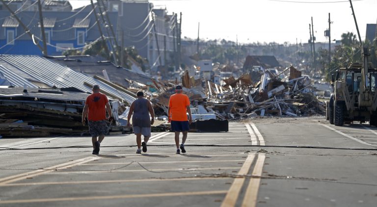 People walk amidst destruction on the main street of Mexico Beach, Fla., in the aftermath of Hurricane Michael on Thursday, Oct. 11, 2018. (AP Photo/Gerald Herbert)