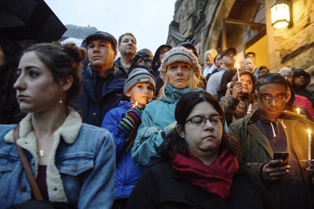 People stand on the stairs of Sixth Presbyterian Church as the crowd spills up the hill and down the street for a vigil blocks from where an active shooter shot multiple people at Tree of Life Congregation synagogue on Saturday, Oct. 27, 2018, in the Squirrel Hill section of Pittsburgh. (Stephanie Strasburg/Pittsburgh Post-Gazette via AP)