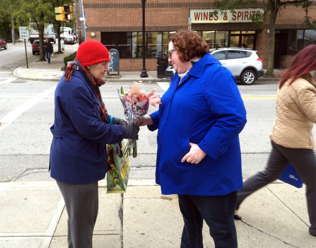 Shooting Synagogue Trump Kristin Wessell, right, hands a bouquet of flowers to Marianne Novy on Murray Avenue in the Squirrel Hill neighborhood of Pittsburgh, Monday, Oct. 29, 2018. Wessell was volunteering to bring some cheer to the neighborhood following Saturday's deadly attack on the nearby Tree of Life synagogue. Neither woman thinks President Trump should come to town. (AP Photo/Allen G. Breed)