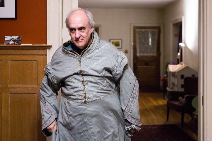 Walt Maguire stands in his Germantown dining room wearing a costume robe of Dumbledore, the Hogwarts headmaster in the Harry Potter series. Maguire dressed as Dumbledore for six years, his final day unexpectedly being Oct. 20, 2017. Now, the festival has rebranded as Witches and Wizards and bears less resemblance to the popular franchise. (Rachel Wisniewski for WHYY)