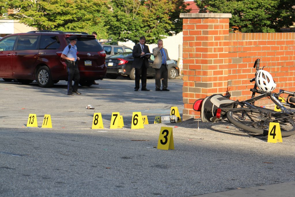 Image uploaded from iOS (3) Philadelphia police investigate the scene of a multiple shooting on Germantown Avenue near Manheim Street Wednesday afternoon. Five men were shot; one later died of his injuries. (Emma Lee/WHYY)