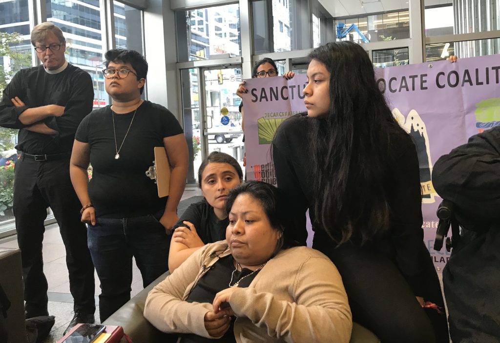 LBcaseysanctuary Carmela Apolonio Hernandez (center), and her daughter Keyri (right), wait in the lobby of 2000 Market Street for a visit with Senator Bob Casey’s staff Wednesday morning. (Laura Benshoff/WHYY)
