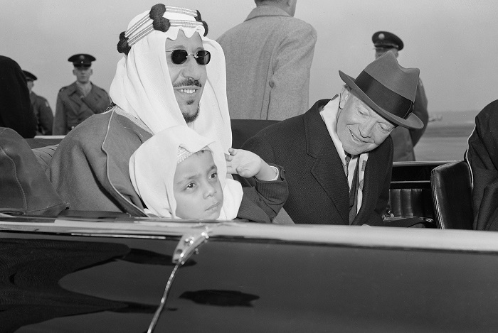 Six-year-old Prince Mashhur ibn Saud waves as he sits on the lap of his father, King Saud of Saudi Arabia, and beside President Eisenhower as they left National Airport, January 30, 1957.  The King and his official party will visit here three days for talks with the President.  (AP Photo)