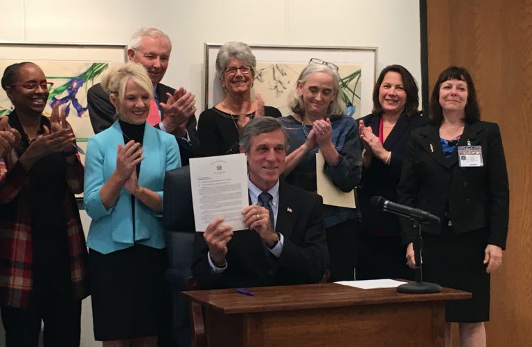 Delaware Gov. John Carney holds up an executive order making Delaware a 