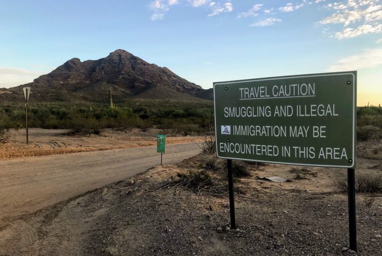 A sign outside Ajo, Ariz., warns hikers to keep an eye out for people who have unlawfully crossed the nearby border with Mexico. (Ryan Lucas/NPR)