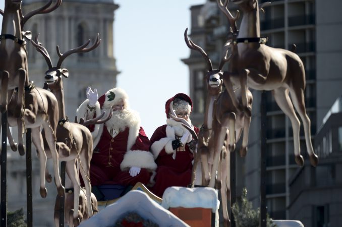 Mr. and Mrs. Claus wave as they close the 99th annual Thanksgiving Day Parade on the Benjamin Franklin Parkway in Philadelphia. (Bastiaan Slabbers for WHYY)