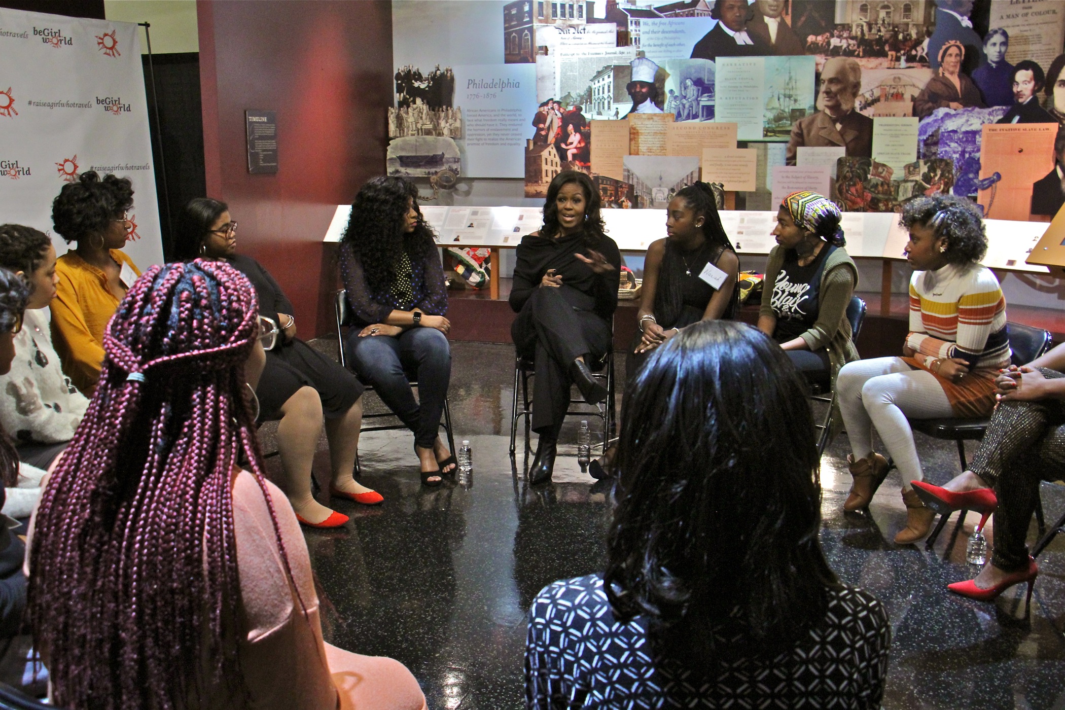 A dozen teens involved in the beGirl.world program, a Philadelphia non-profit that encourages travel and global education for girls, meet with former first lady Michelle Obama at the African American Museum in Philadelphia.